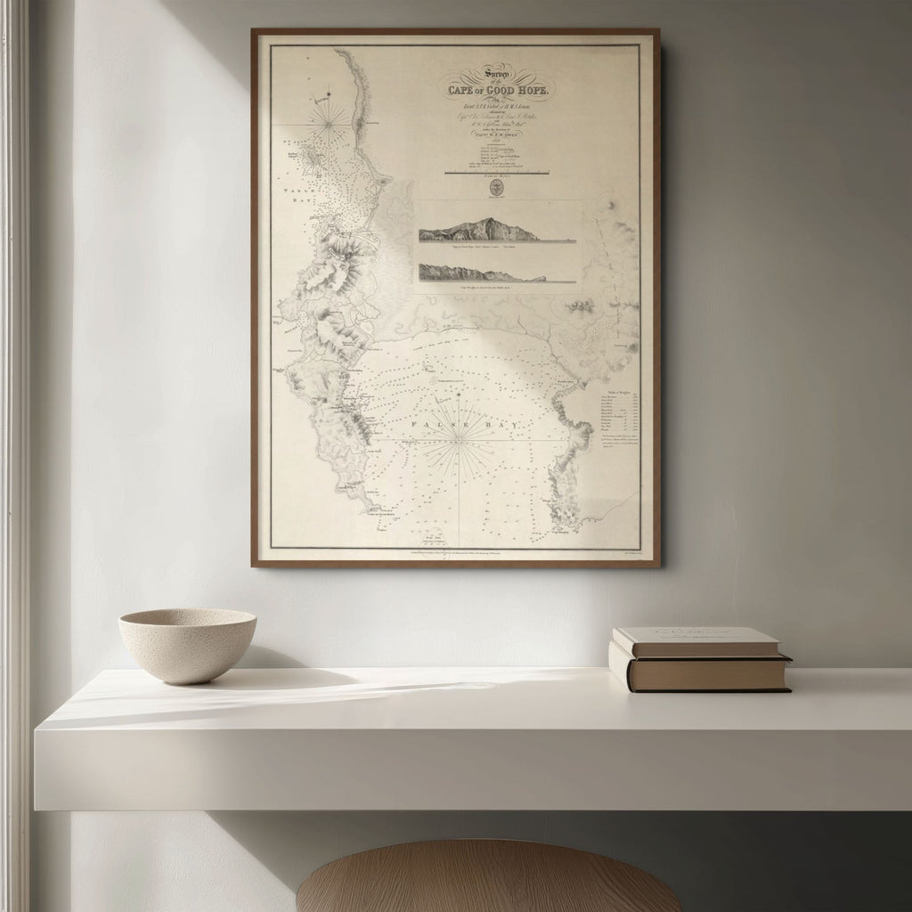 1822 chart of Cape of Good Hope on cream wall above a cream shelf with books and a bowl, some light coming in from the side