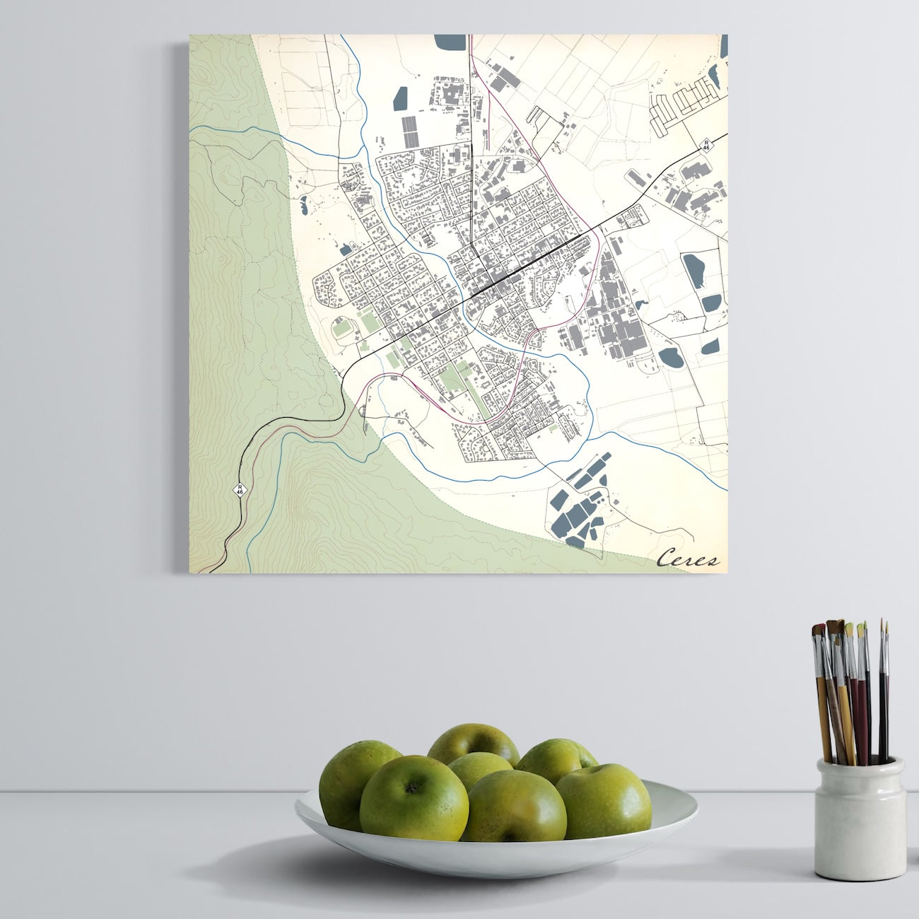Canvas print of Ceres Classic map on wall with bowl of apples and paint brushes in foreground.