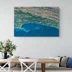 Garden Route 2 East satellite print hung on a white wall above a dining table, showing deep blue ocean currents against the green coastal mountains.