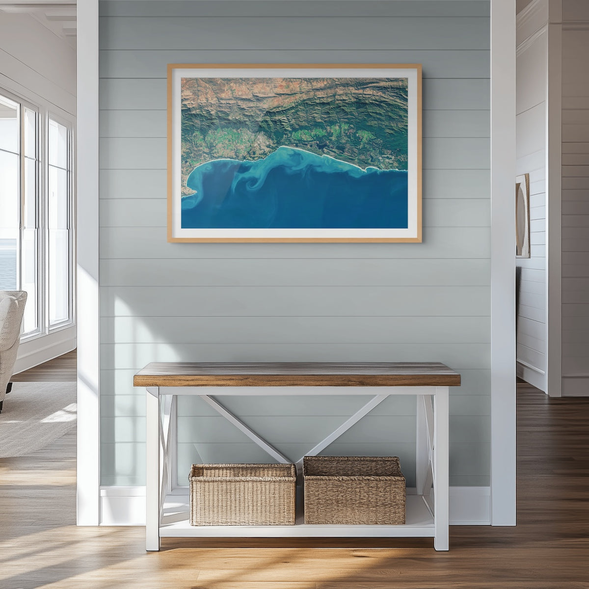 Garden Route 2 West satellite print in a light oak frame above a console table, showing the coast with the Little Karoo beyond the Outeniqua Mountains.