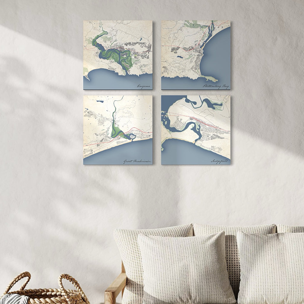 Gallery wall of four Garden Route town map prints in the Classic style — Knysna, Great Brak, Sedgefield, Plettenberg Bay — arranged in a 2×2 grid next to a sofa