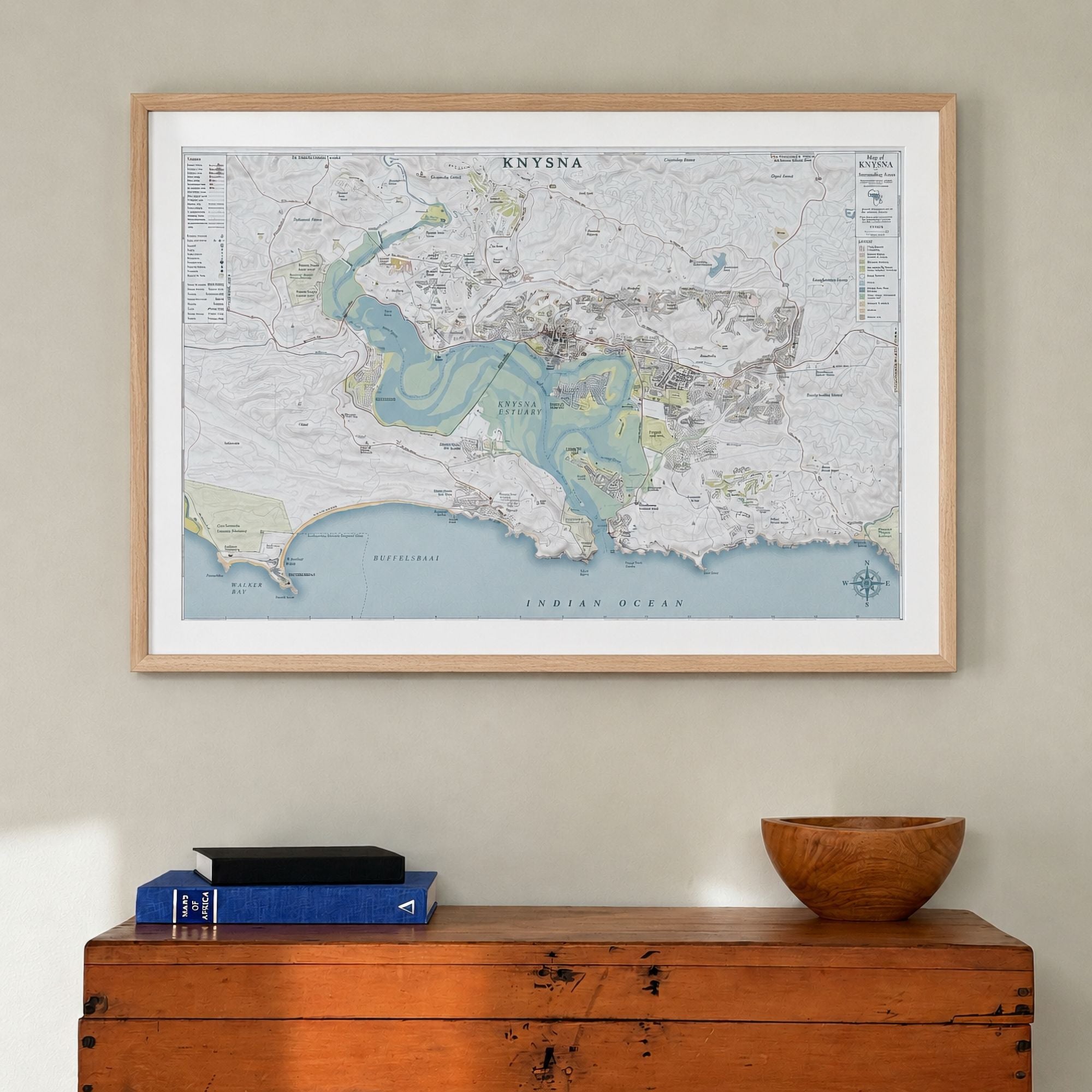 Knysna large map print in the Classic style, in a light wood frame with a wide white mount, hung above a wooden chest