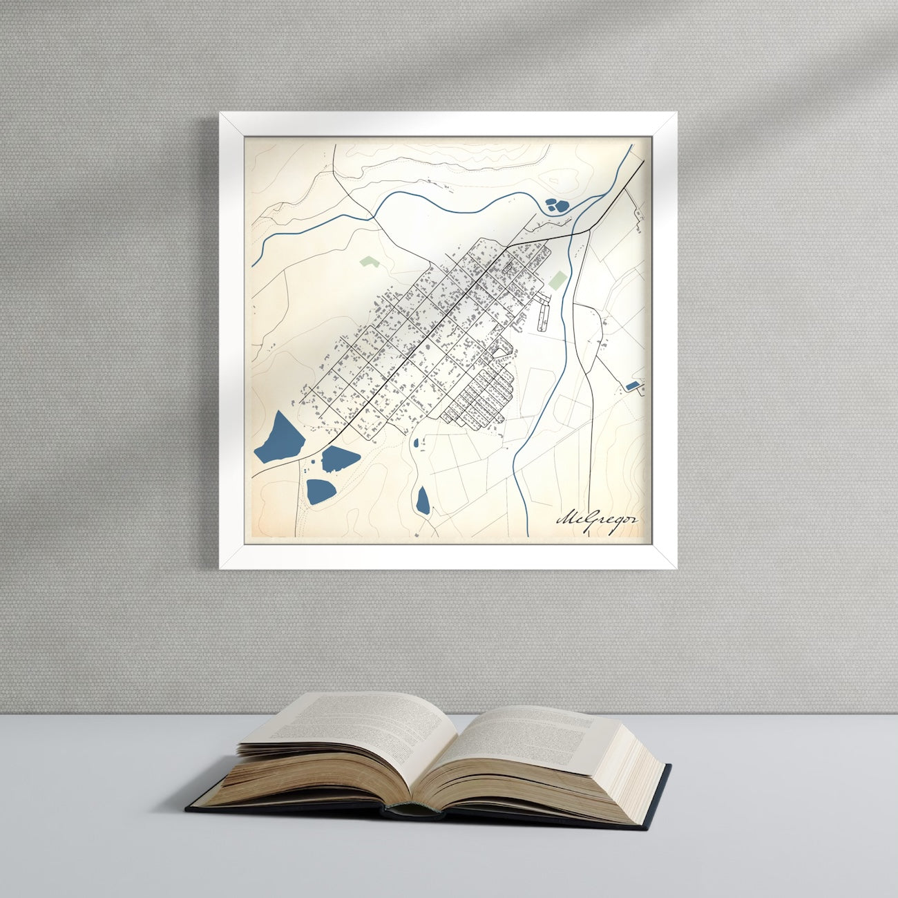 McGregor Classic map print in white frame above flat surface with open book.